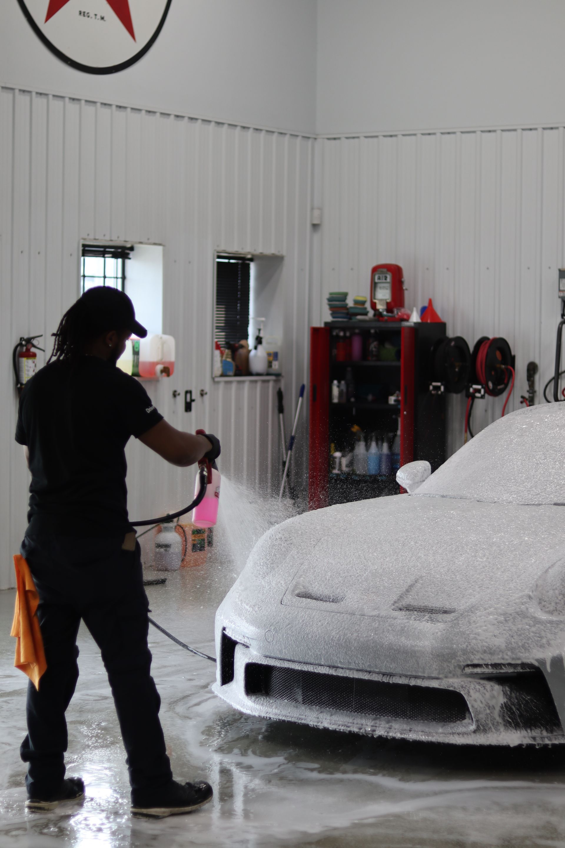 Person spraying foam on a car in a car wash bay