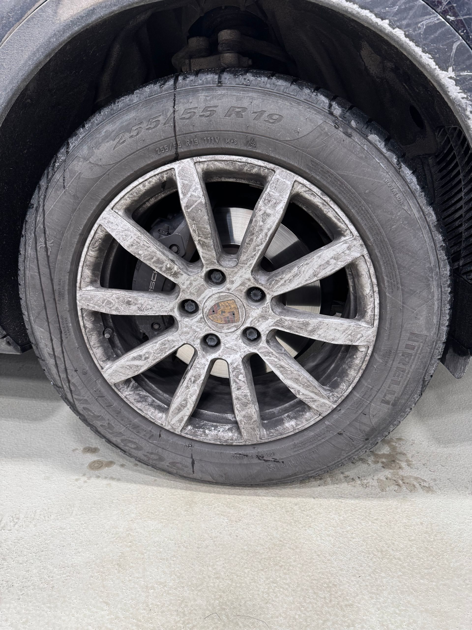 Dirty car wheel with flat tire on a vehicle in a garage area