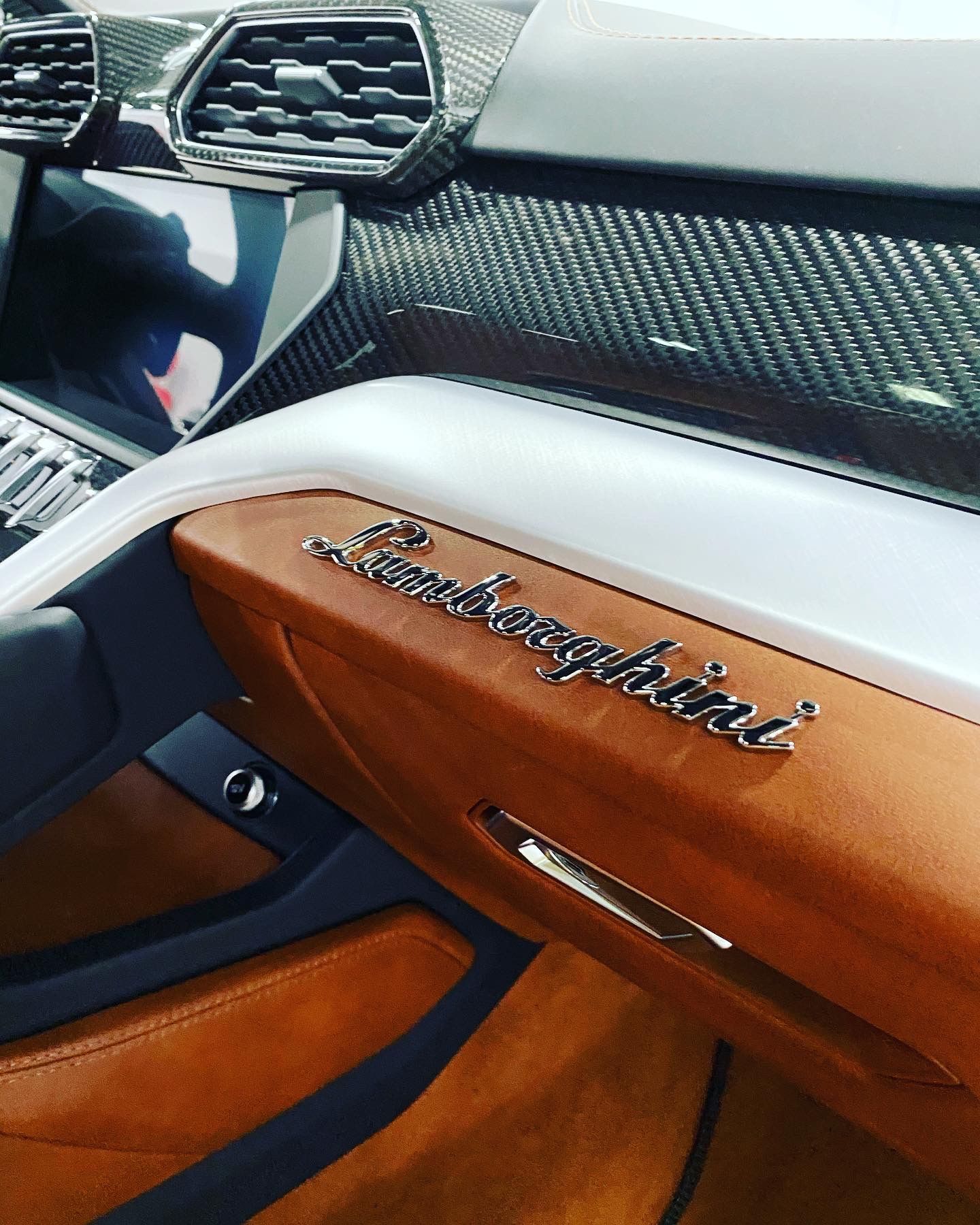 Lamborghini interior with tan leather door trim and carbon fiber dashboard accents