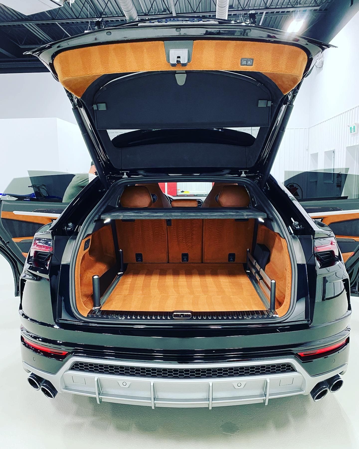 Black SUV with rear hatch open, showing a wood-lined cargo area in a showroom.