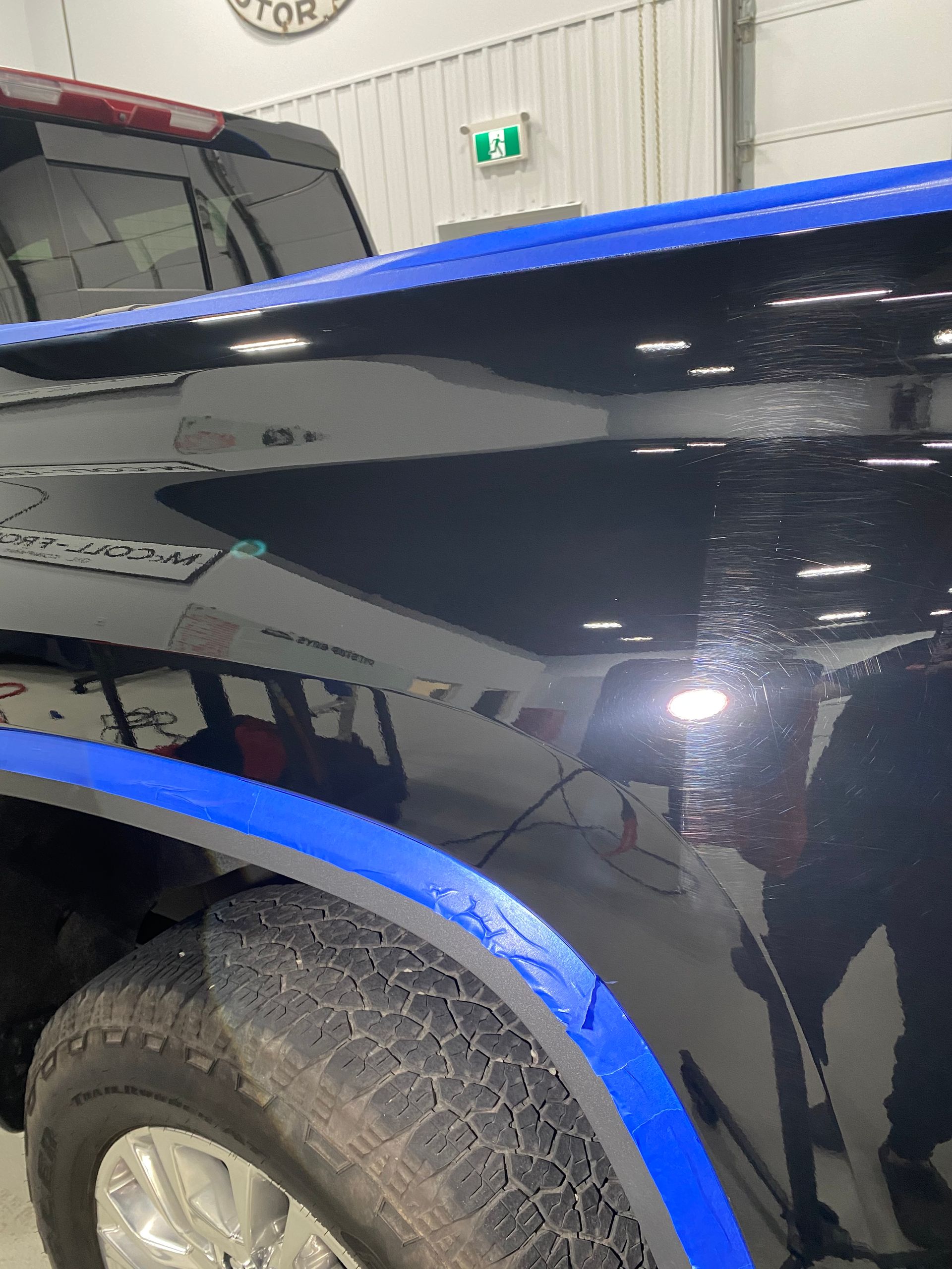 Glossy black pickup truck with bright blue trim, parked indoors under garage lights