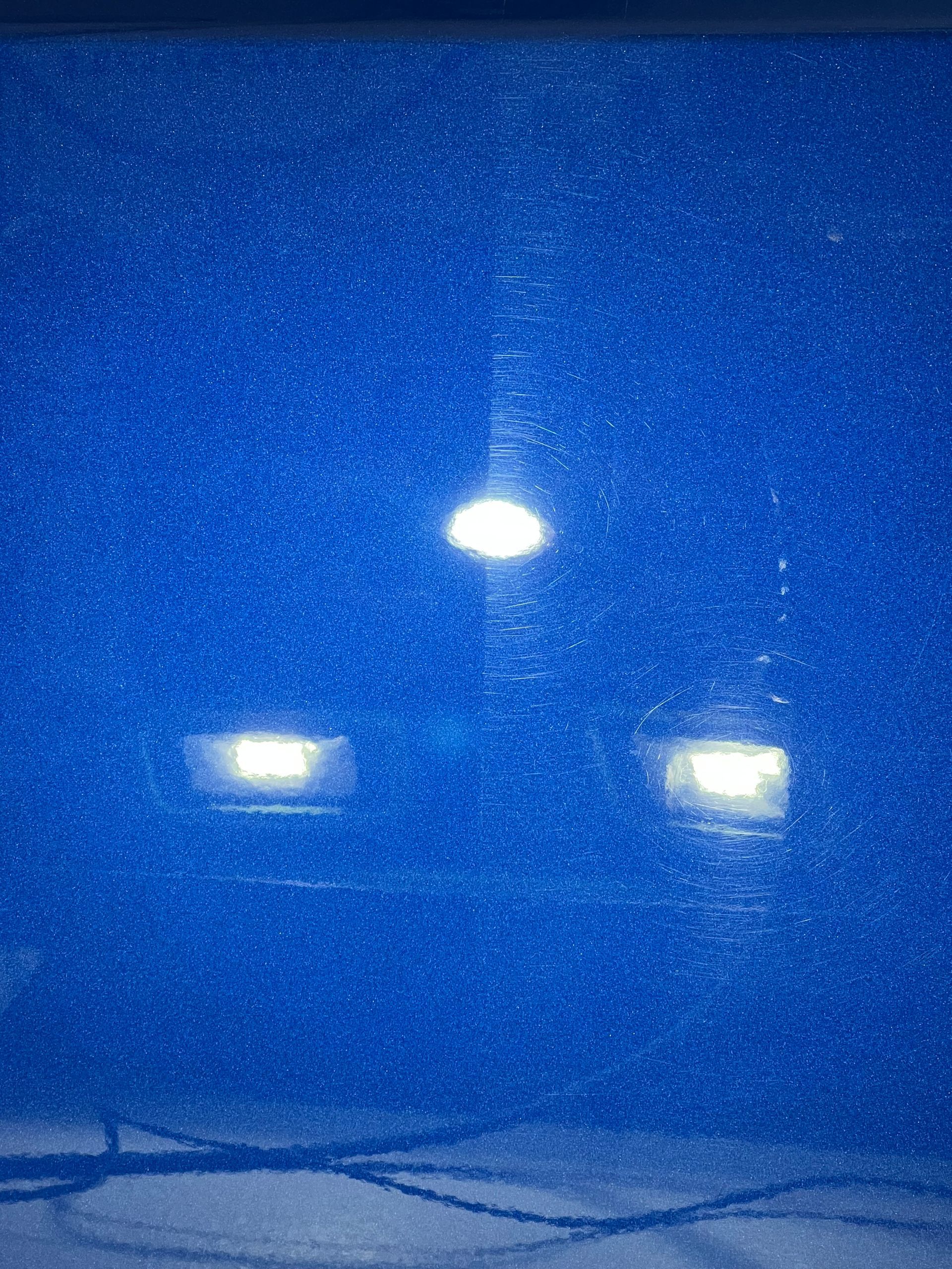 Snowy night with two bright headlights and a glowing streetlight in the distance