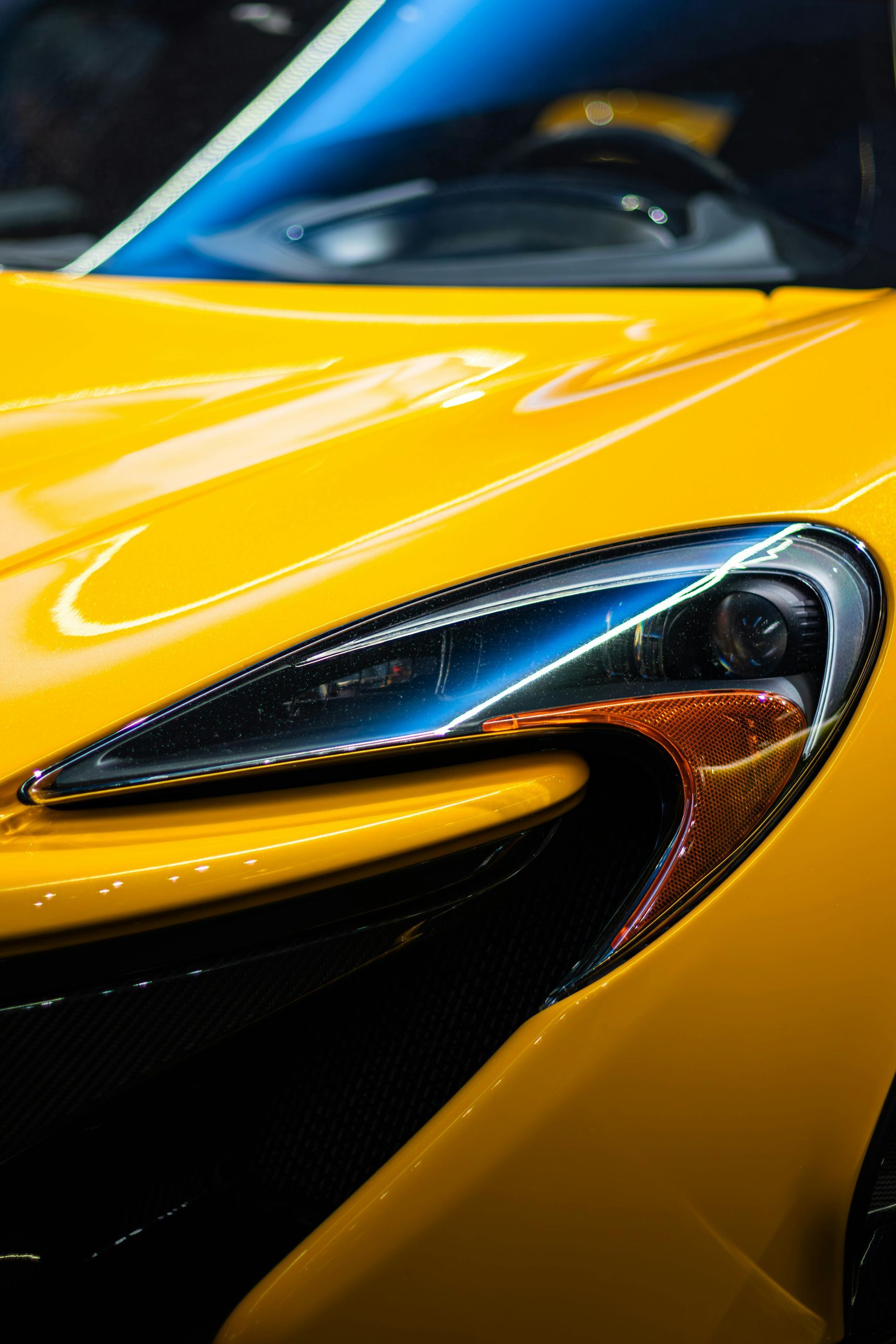 Close-up of a yellow sports car headlight and front fender with glossy reflections