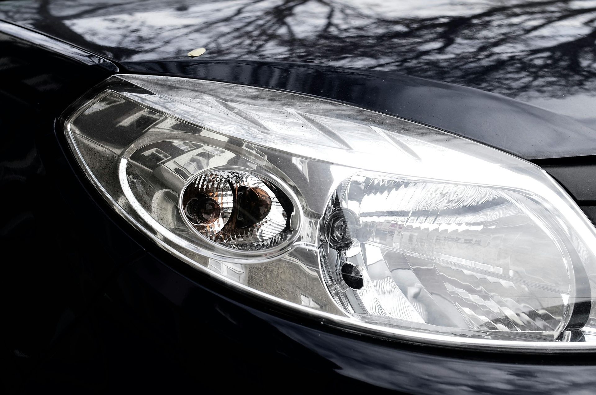 Close-up of a silver car headlight on a black vehicle