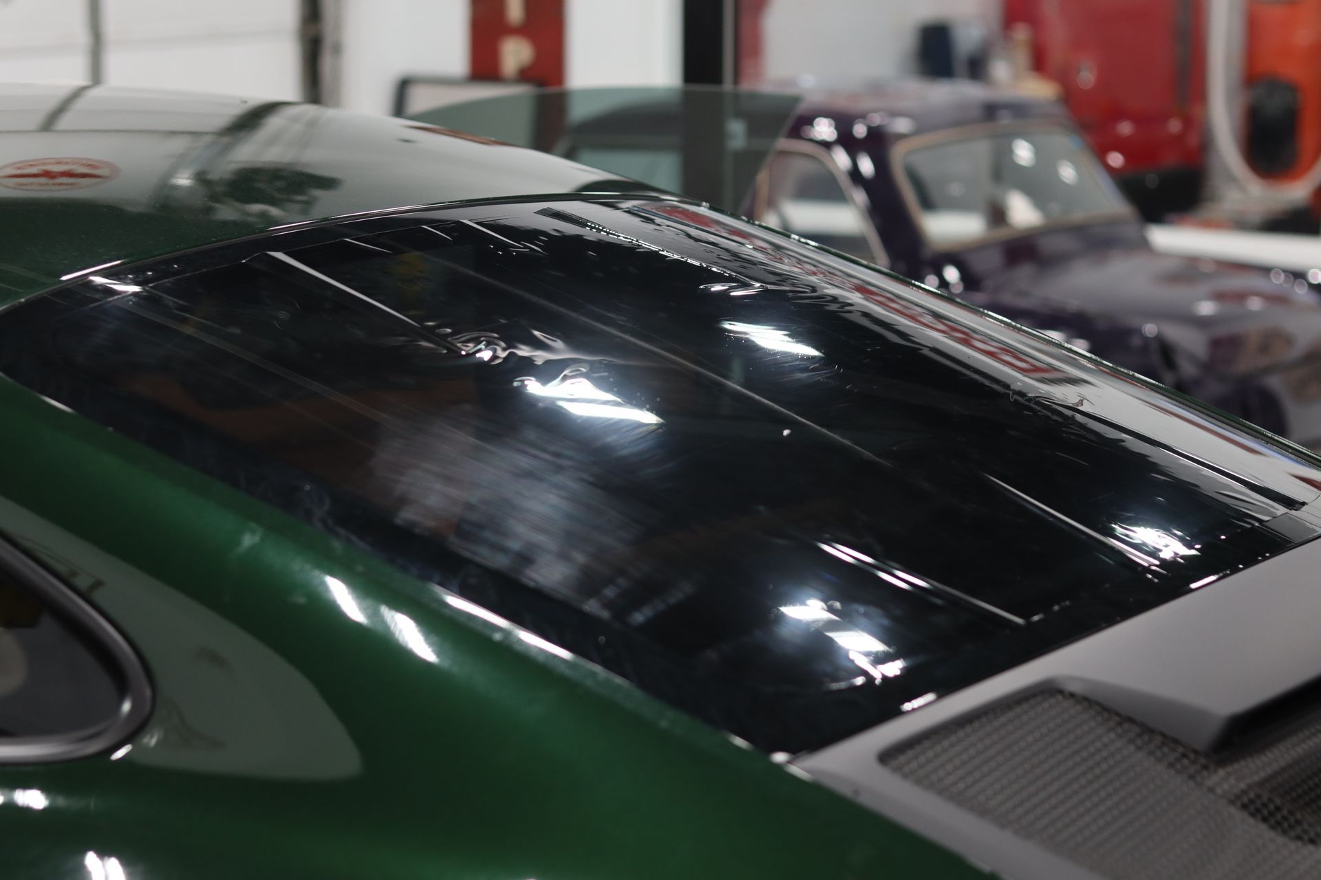 Green sports car with a black roof in a garage, shown close-up from above