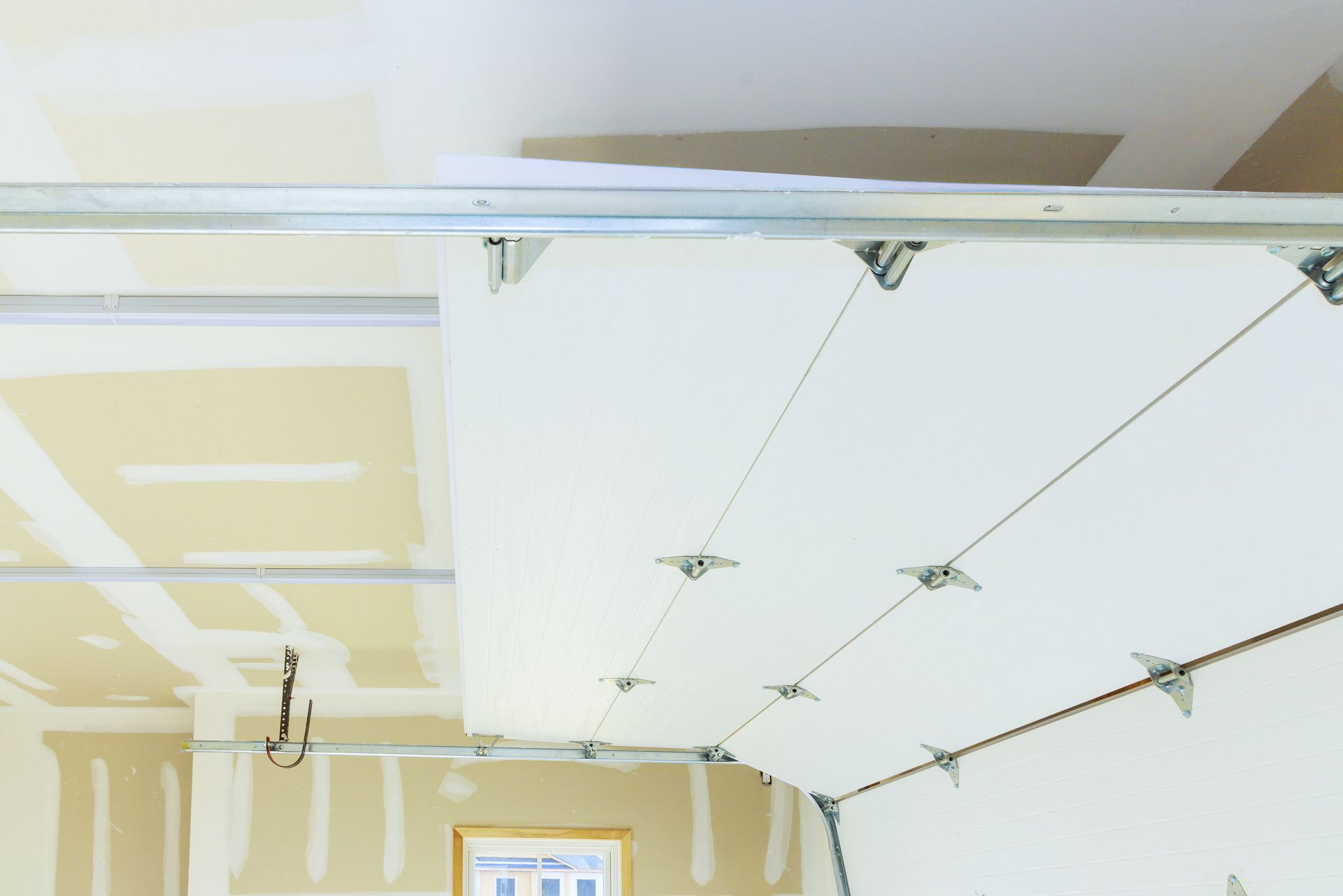 Unfinished garage ceiling with white drywall panels and metal tracks under construction