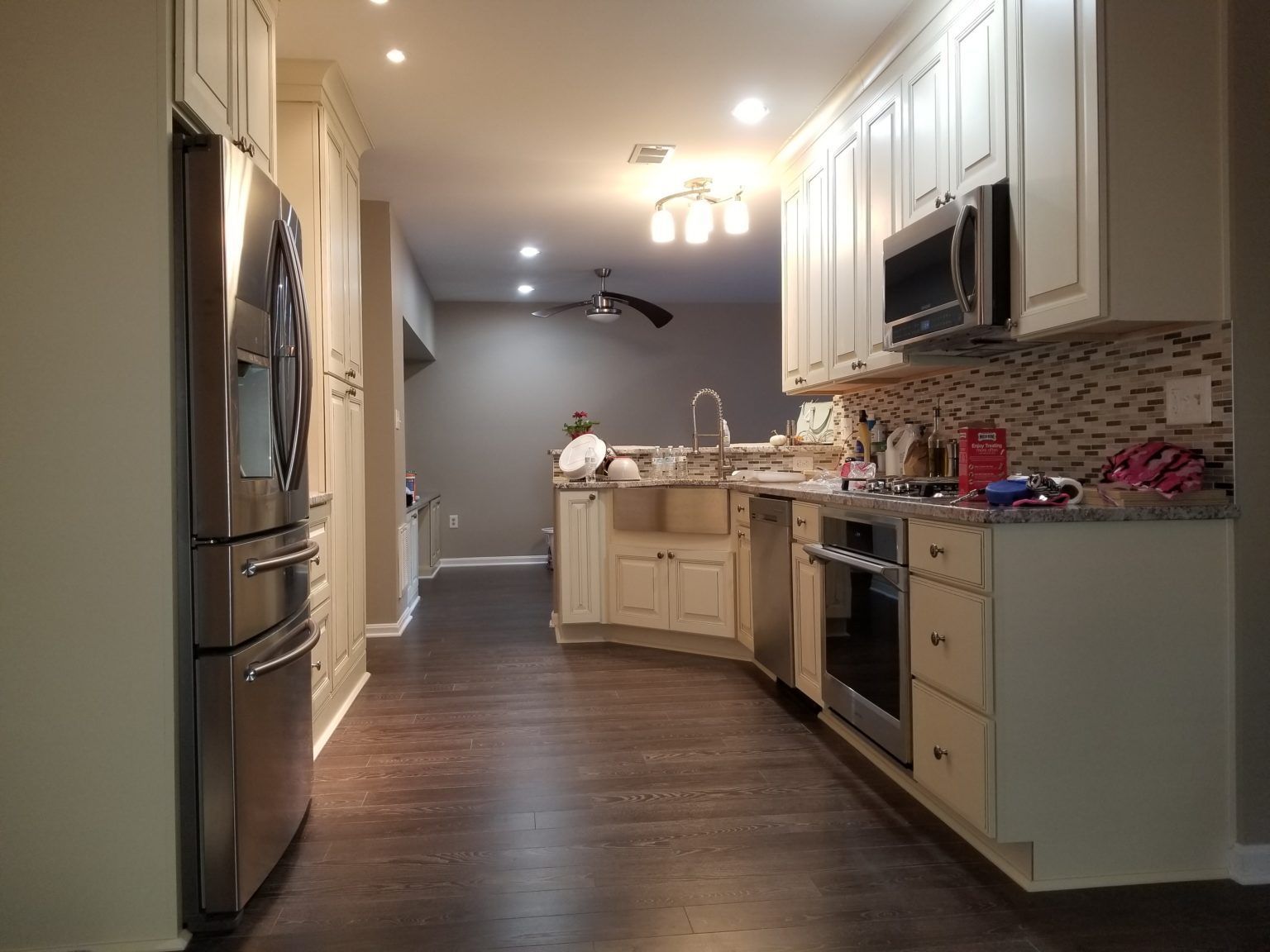 Kitchen with white cabinets, stainless steel appliances, dark wood floor, and tan walls.