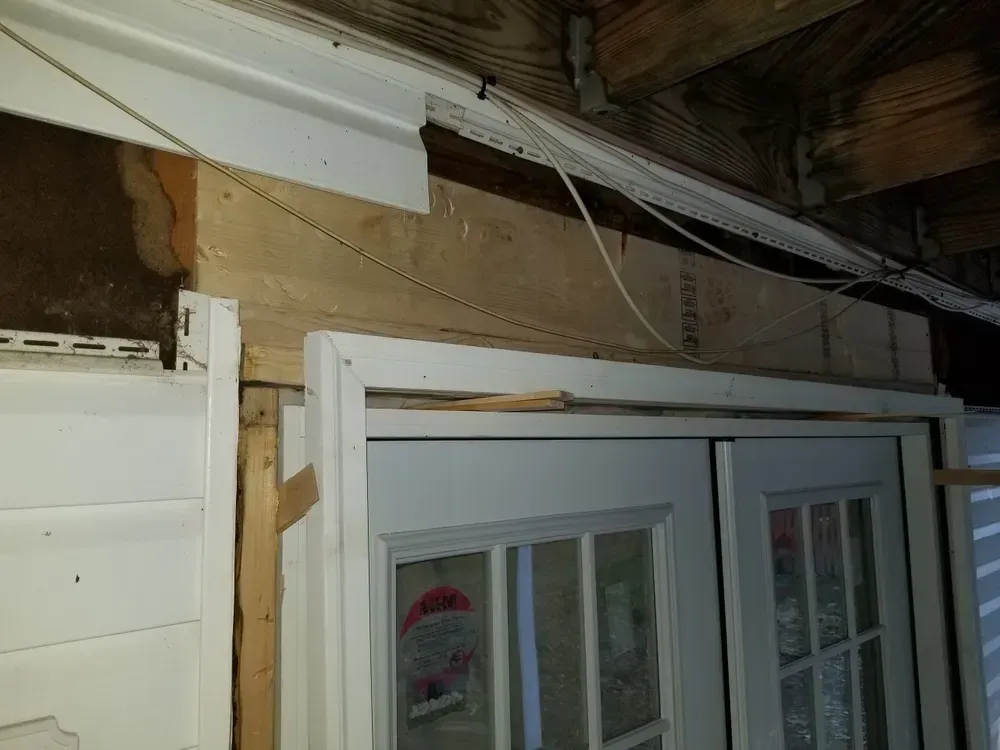 Exterior doors framed with wood, beneath siding and a wire.