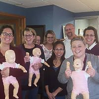 A group of people are standing next to each other holding dolls.