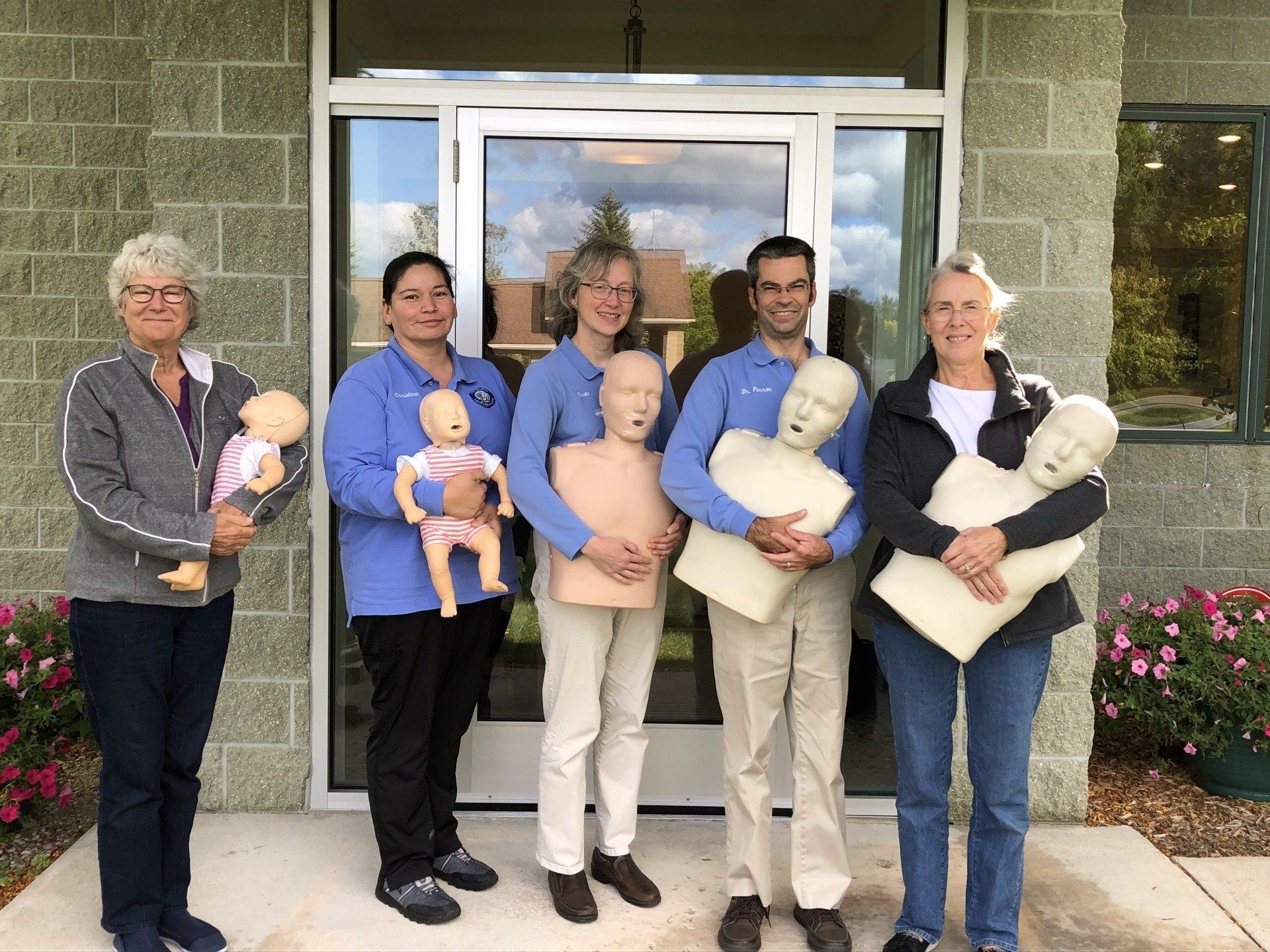A group of people standing in front of a building holding mannequins.