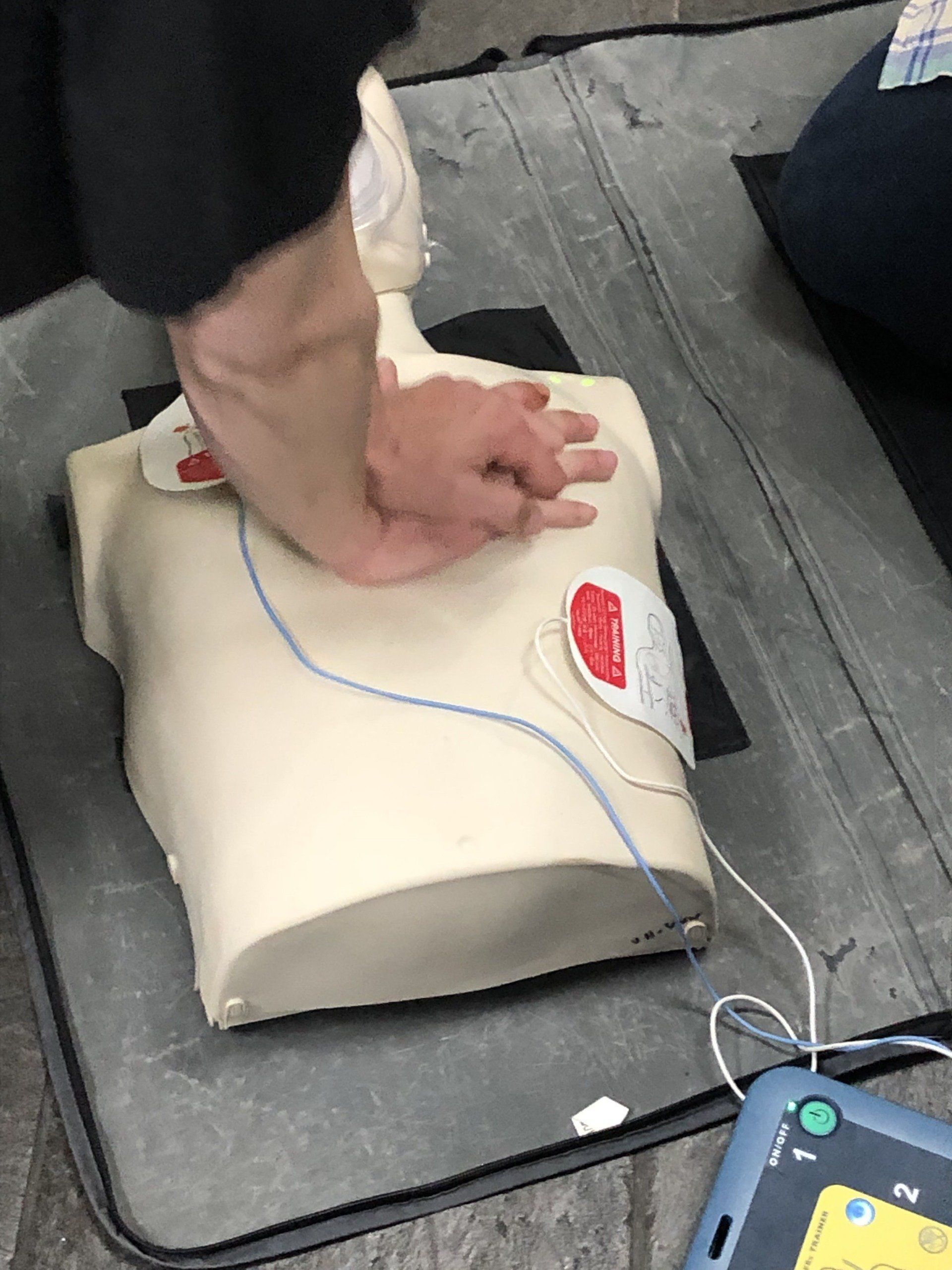 A person is using a defibrillator on a mannequin.
