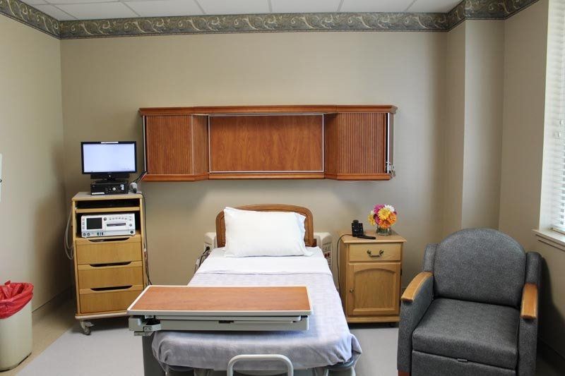 A hospital room with a bed a chair and a computer
