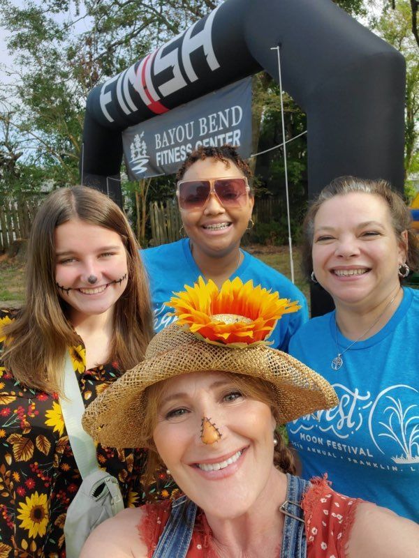 3 women standing outside in front of a blow-up finish line for a 5k race. 