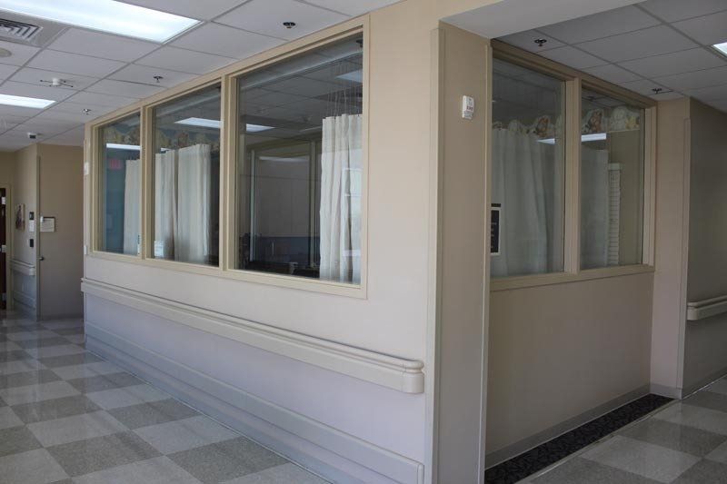 A hospital hallway with a lot of windows and curtains.