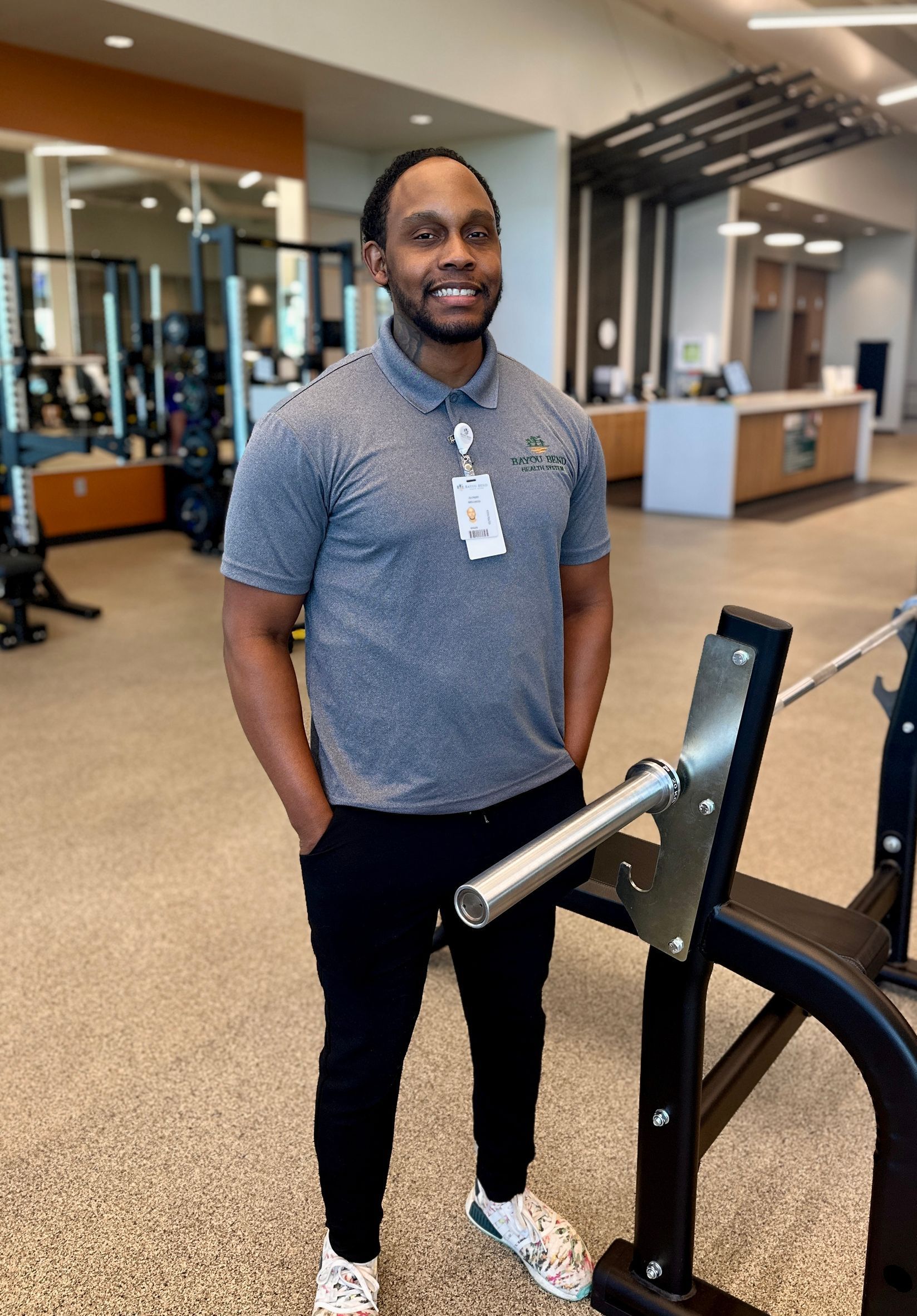 A man is standing next to a barbell in a gym.
