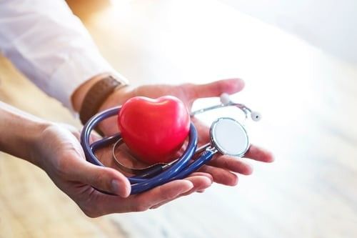 Physician's hands holding out a heart and a stethescope 
