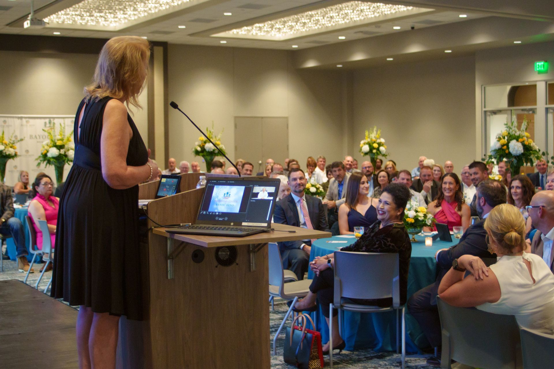 A woman is standing at a podium giving a presentation to a crowd of people.