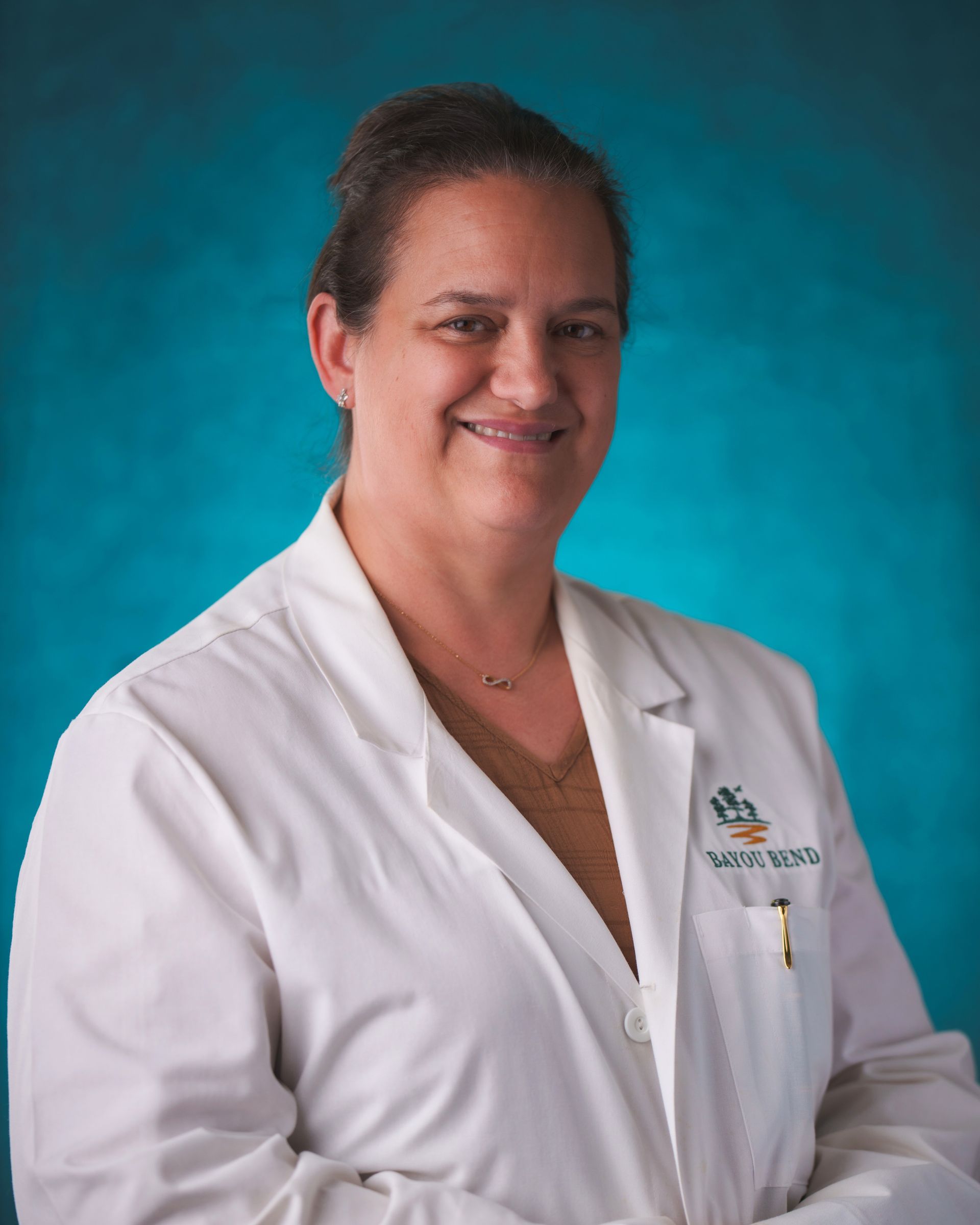 A woman in a white lab coat is smiling for the camera.