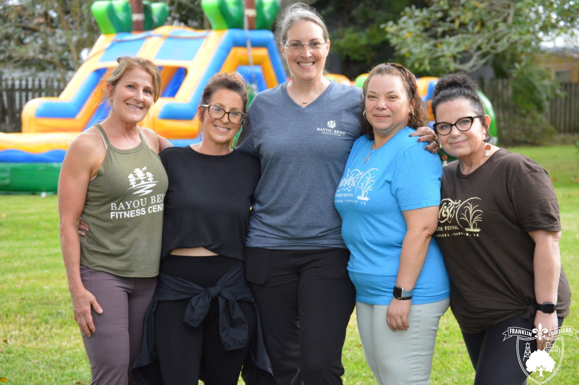 5 women standing outside in front of a blow-up obstacle course