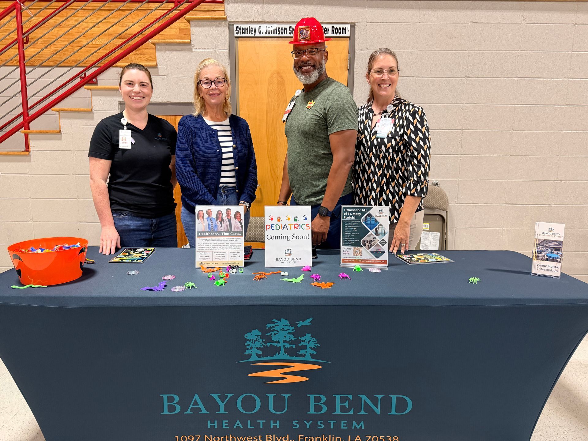 3 women and 1 man standing at an information table inside a community center