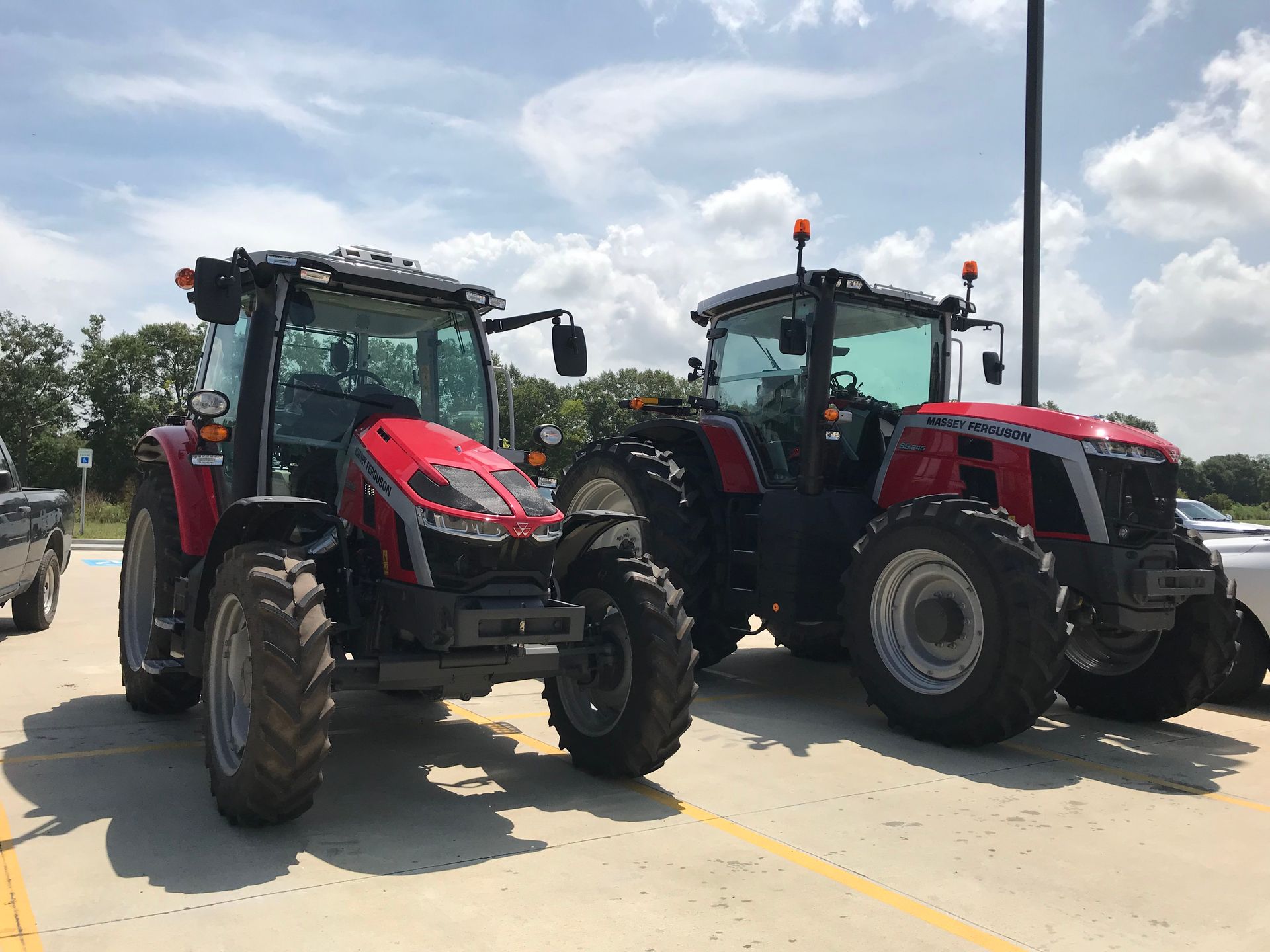 Two tractors are parked next to each other in a parking lot.