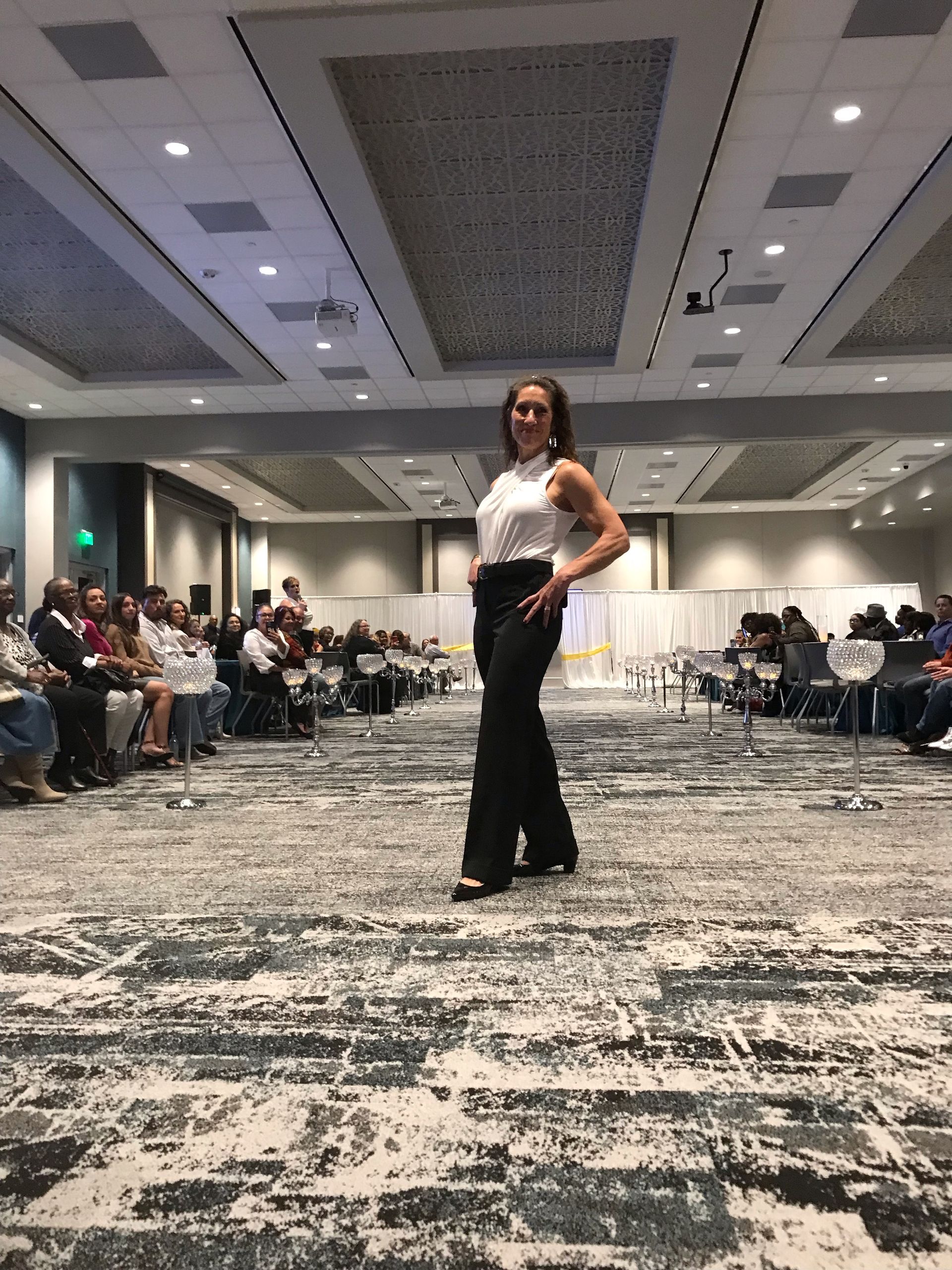 A woman is walking down a runway at a fashion show.