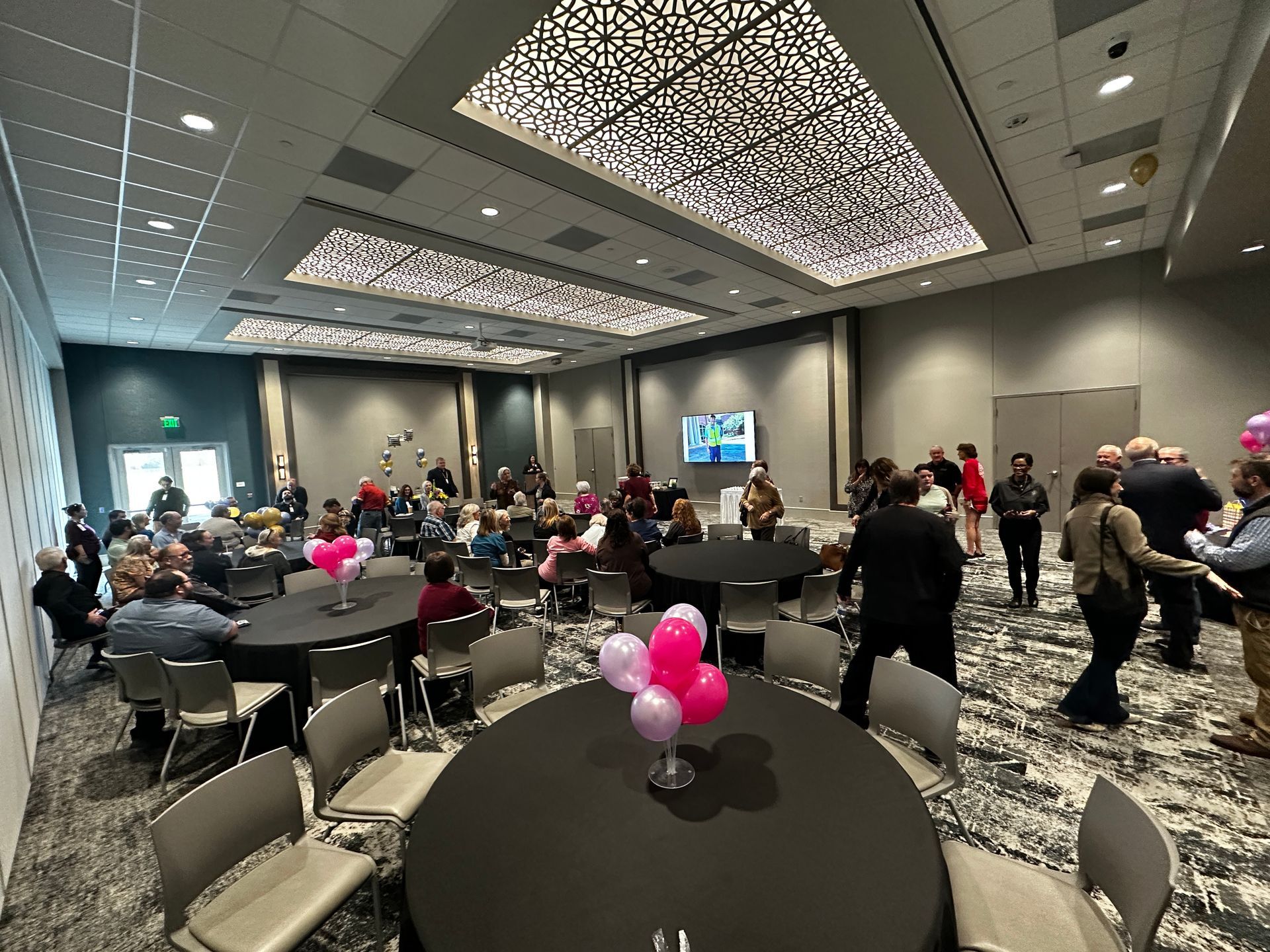 A large room with tables and chairs and balloons on them