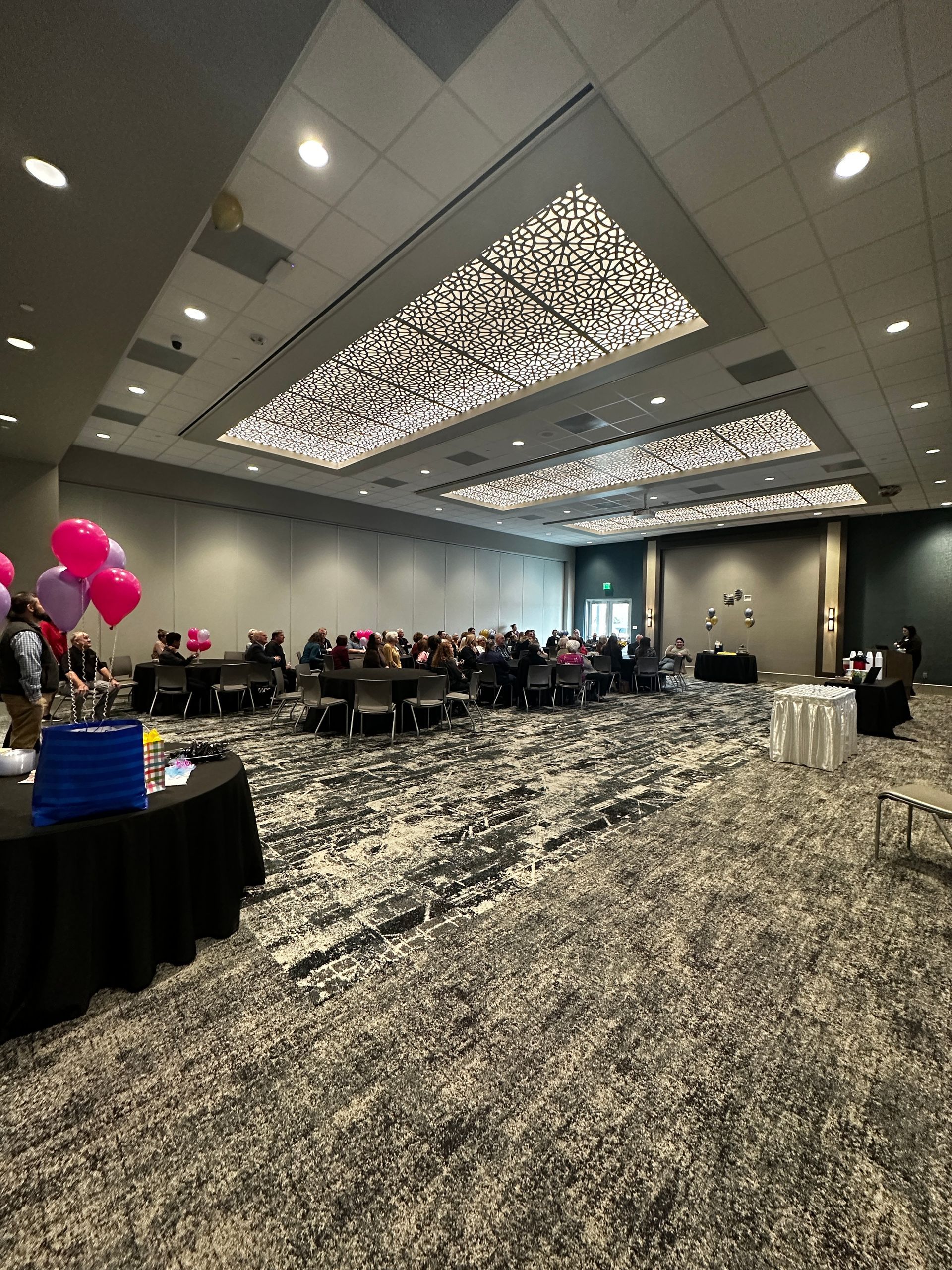 A large room with tables and chairs and balloons on the ceiling