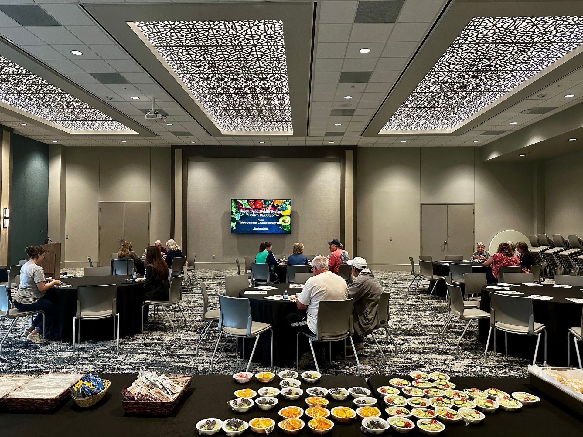 A group of people are sitting at tables in a large room.