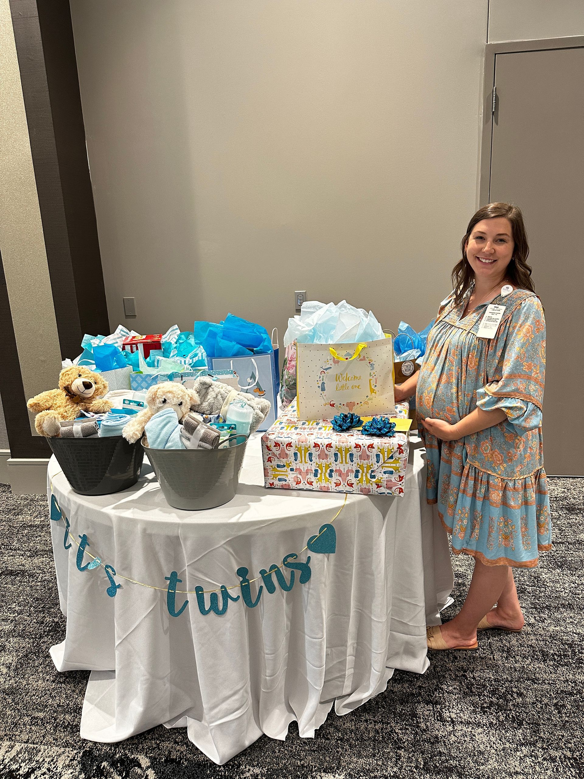 A pregnant woman is standing in front of a table decorated for a baby shower.