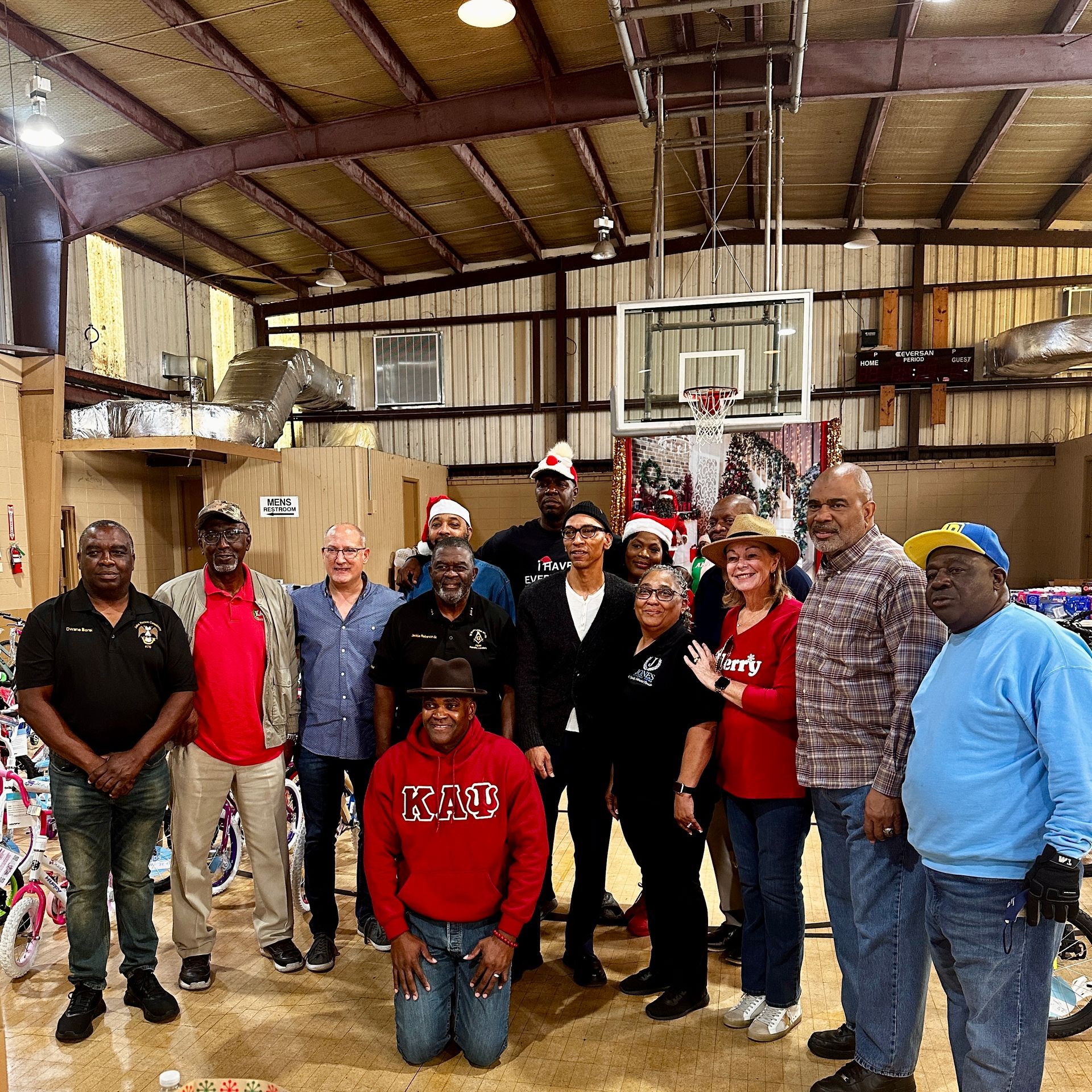 Group of people in a community center standing in front of bicycles and toys
