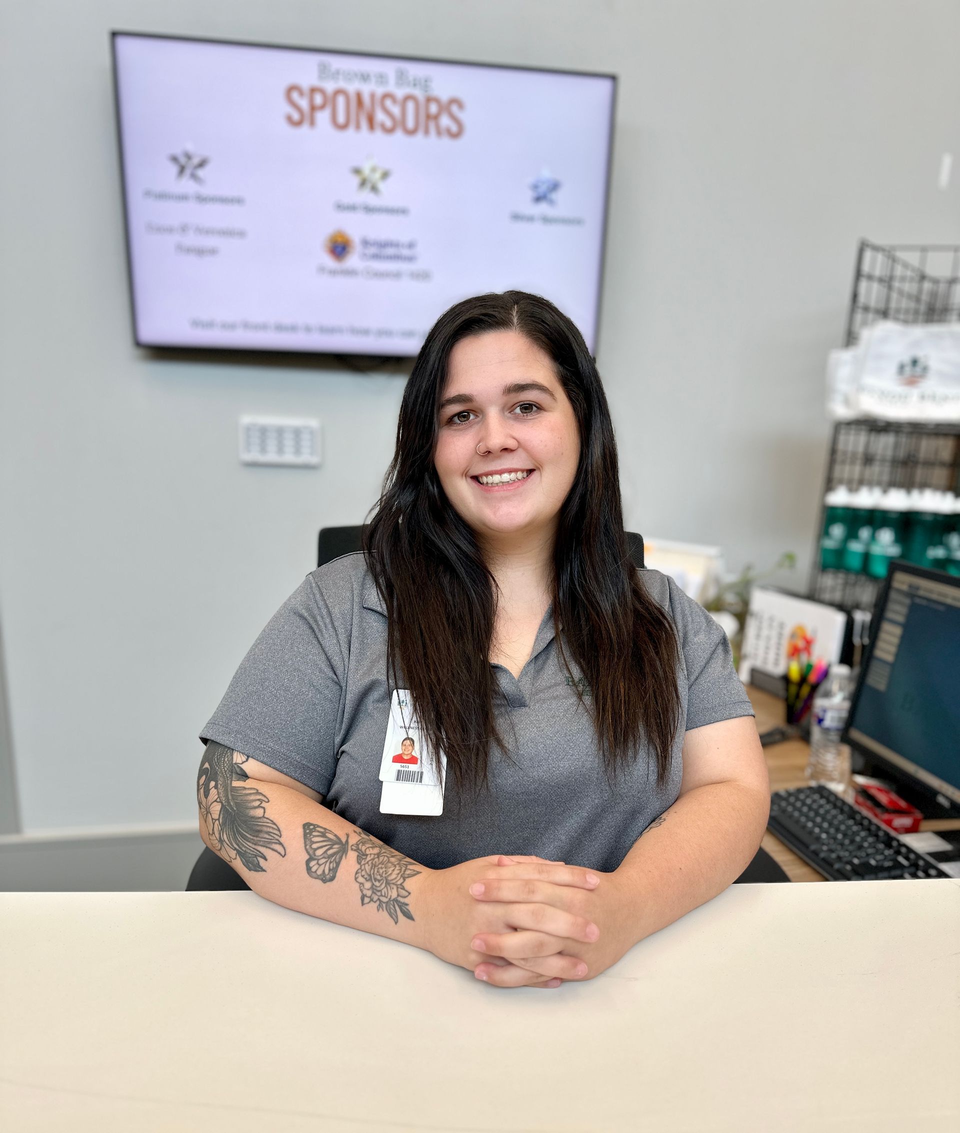A woman smiling at the gym's front desk