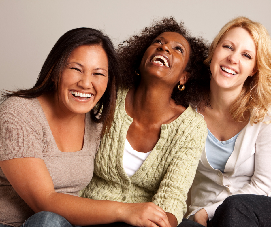 Three women are sitting next to each other and laughing