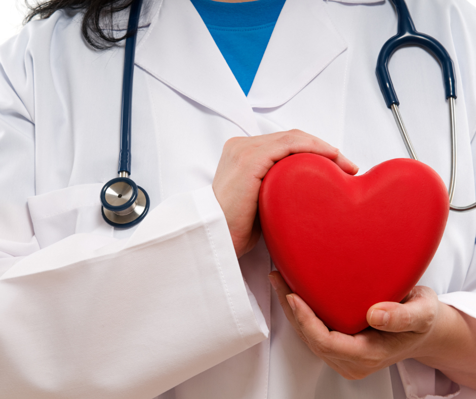 A doctor with a stethoscope around her neck is holding a red heart