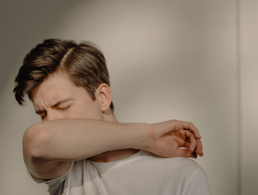 A man is coughing into his elbow.