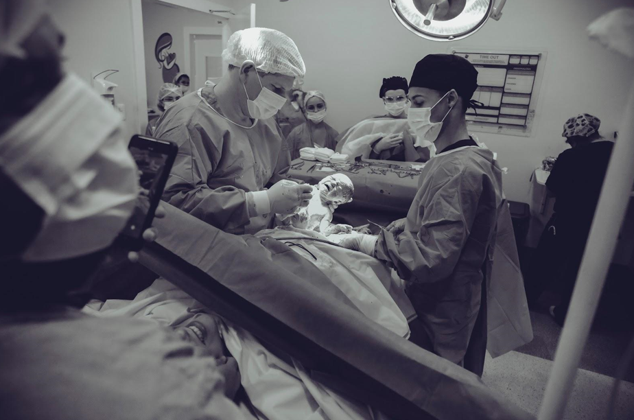 A group of surgeons are performing surgery on a patient in an operating room.