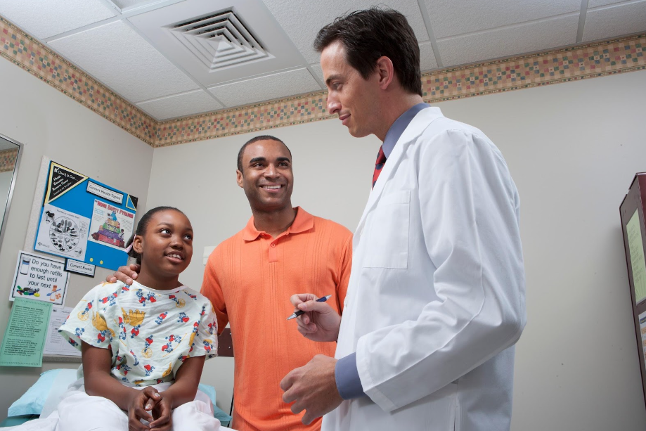 A doctor is talking to a patient and her father in a hospital room.