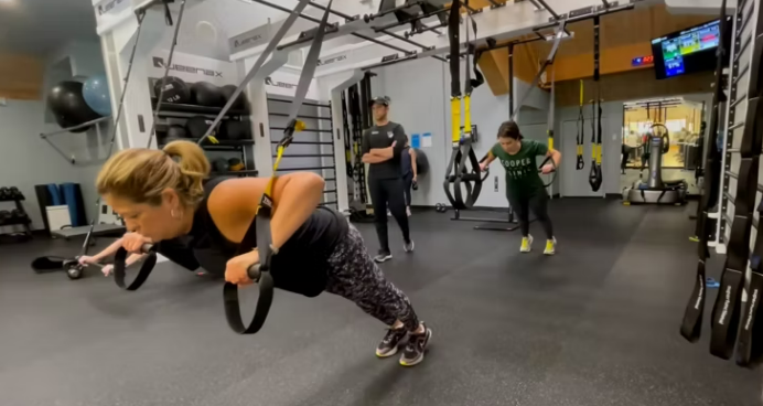 A group of people are doing push ups in a gym.