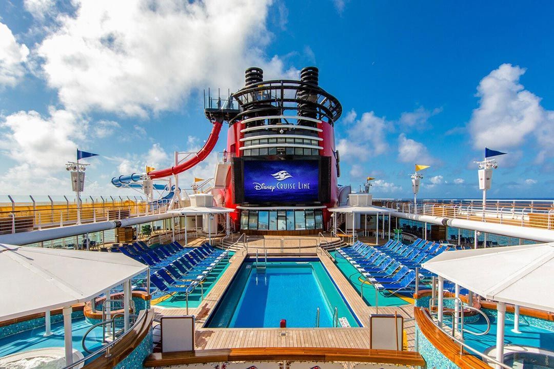 Cruise ship deck with pool, waterslides, and lounge chairs under a bright blue sky