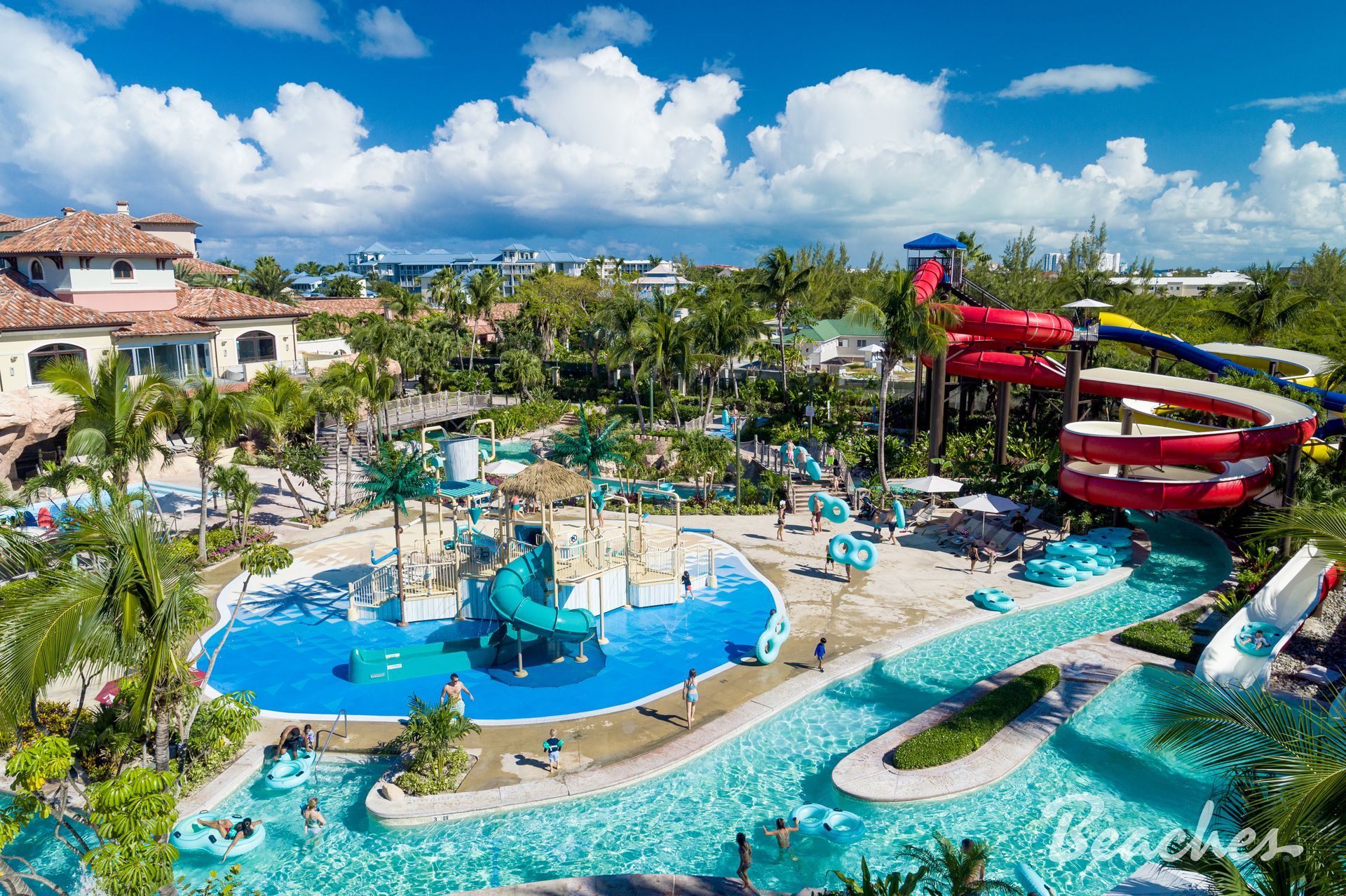 Resort water park with pools, slides, and tropical landscaping under a blue sky