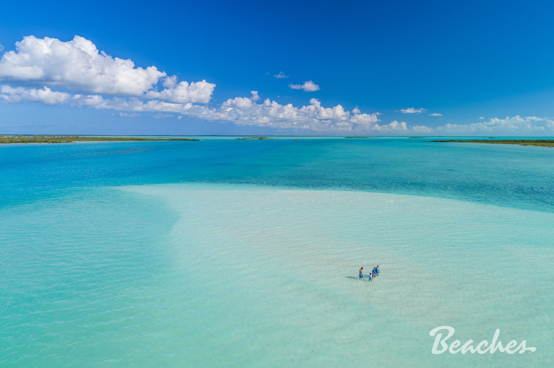 Turquoise tropical beach with calm water, blue sky, and a small boat near shore