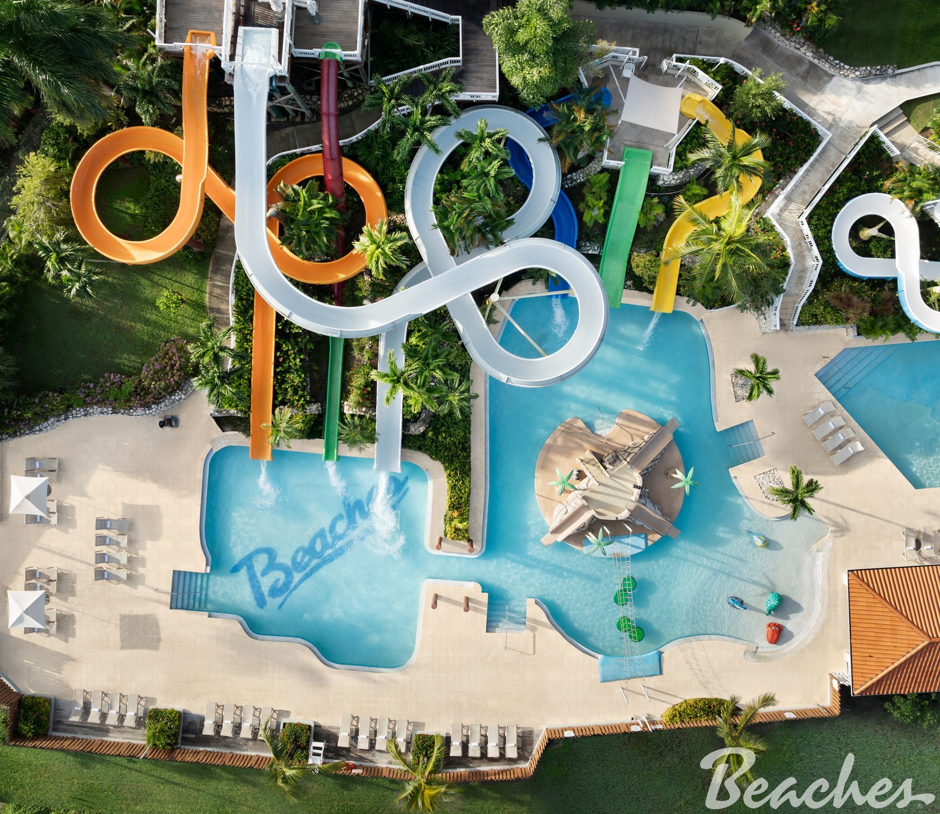 Aerial view of a colorful waterpark with winding slides and a blue pool labeled “Beaches.”