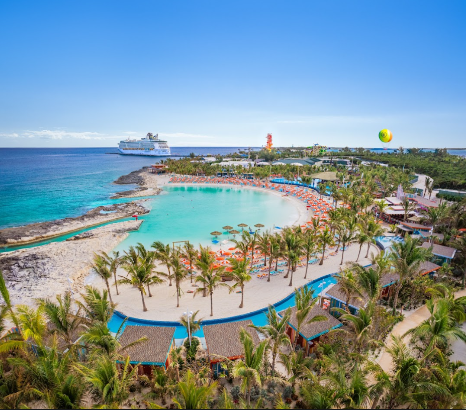 Tropical beach resort with a turquoise lagoon, palm trees, sandy shore, and cruise ship offshore