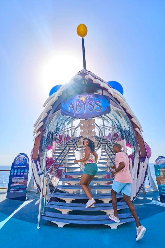 Two women climbing into a bright blue AYS bus pod under a sunny sky