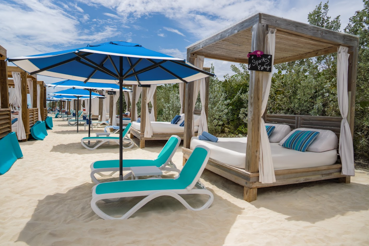 Beach cabana with turquoise loungers and blue umbrellas on a sandy resort shoreline