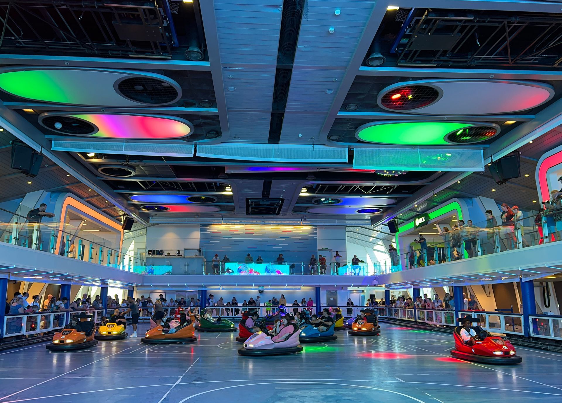 Indoor bumper car arena with colorful ceiling lights and people riding bumper cars