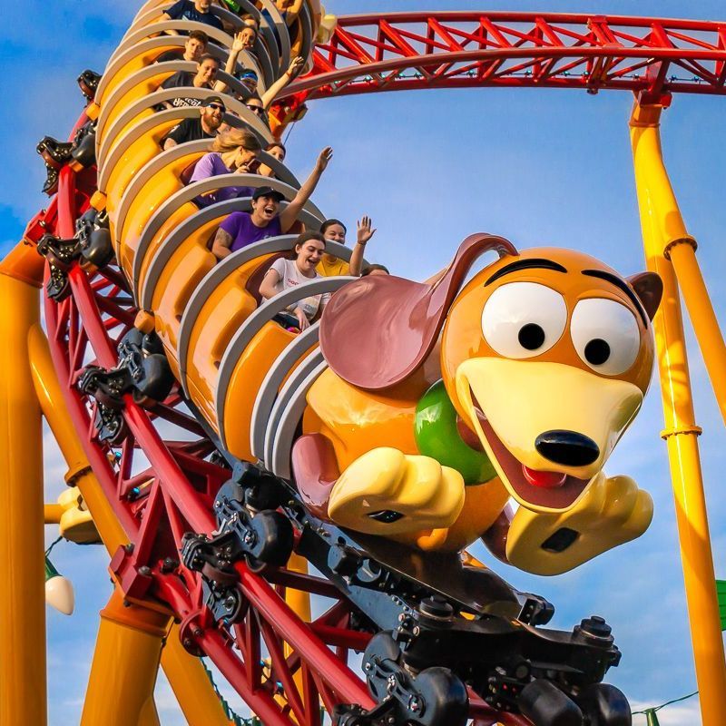 Cartoon dog roller coaster with riders on a red track against a blue sky