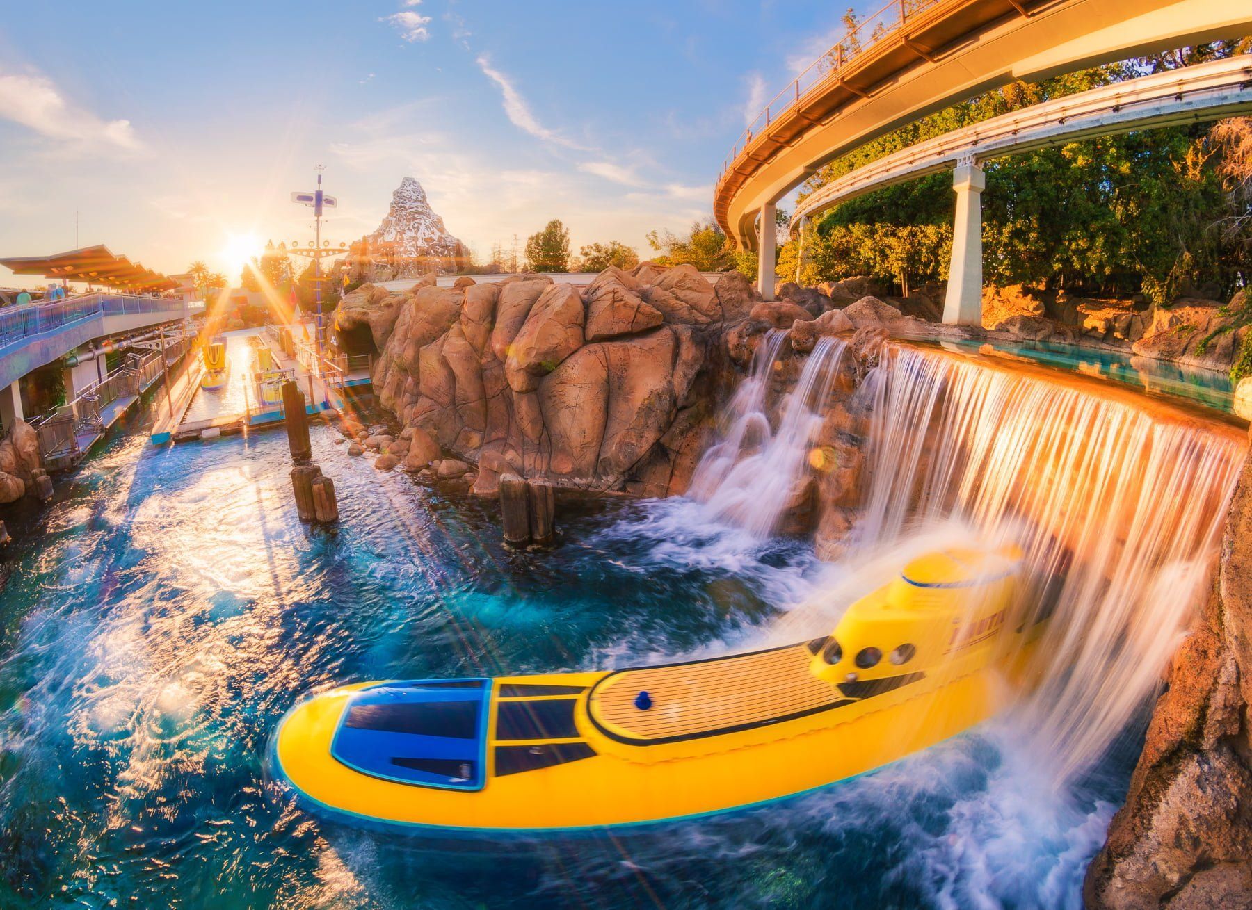 Yellow boat at a waterfall ride in a rocky water park at sunset