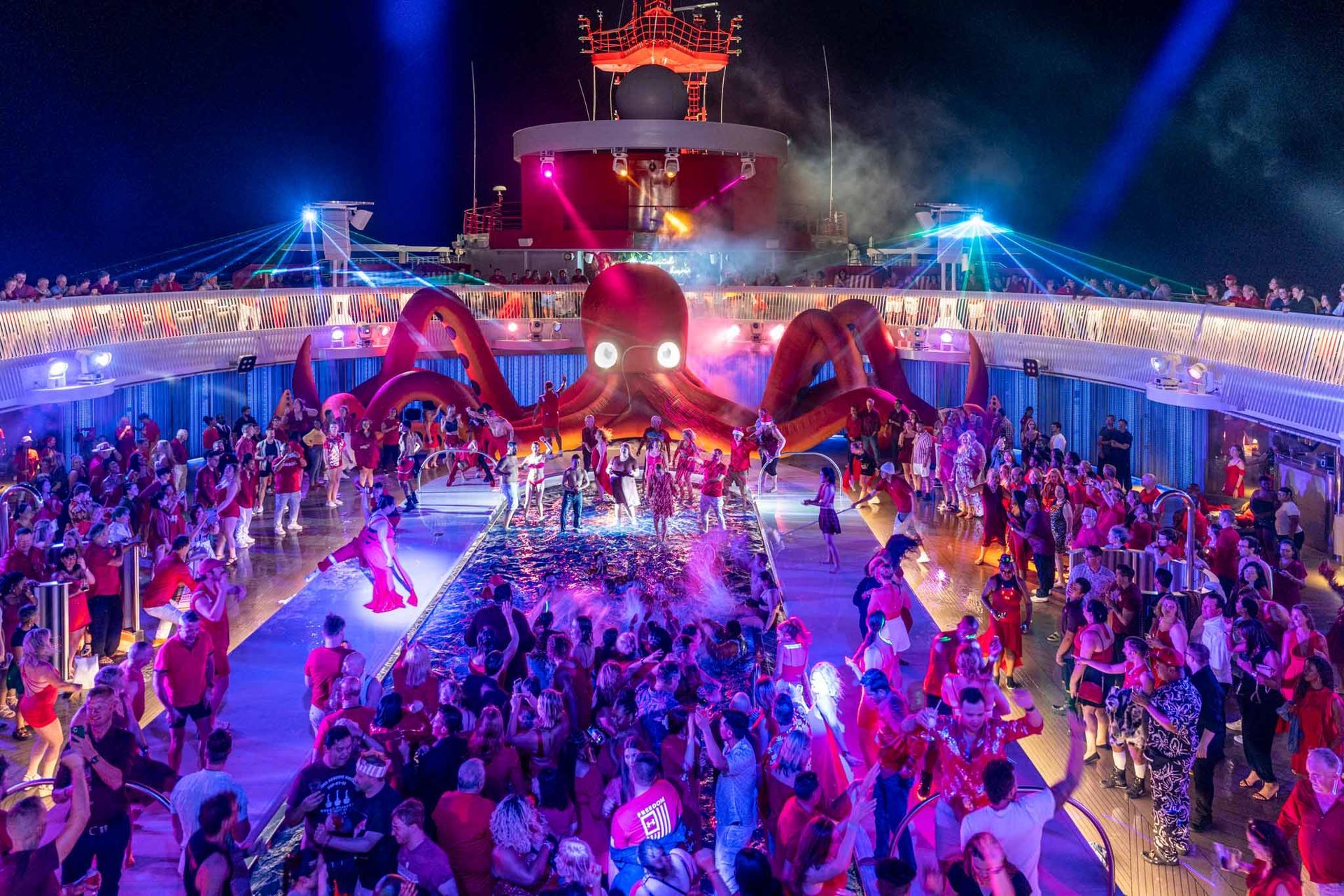 Crowded neon-lit festival dance floor under a red octopus stage at night