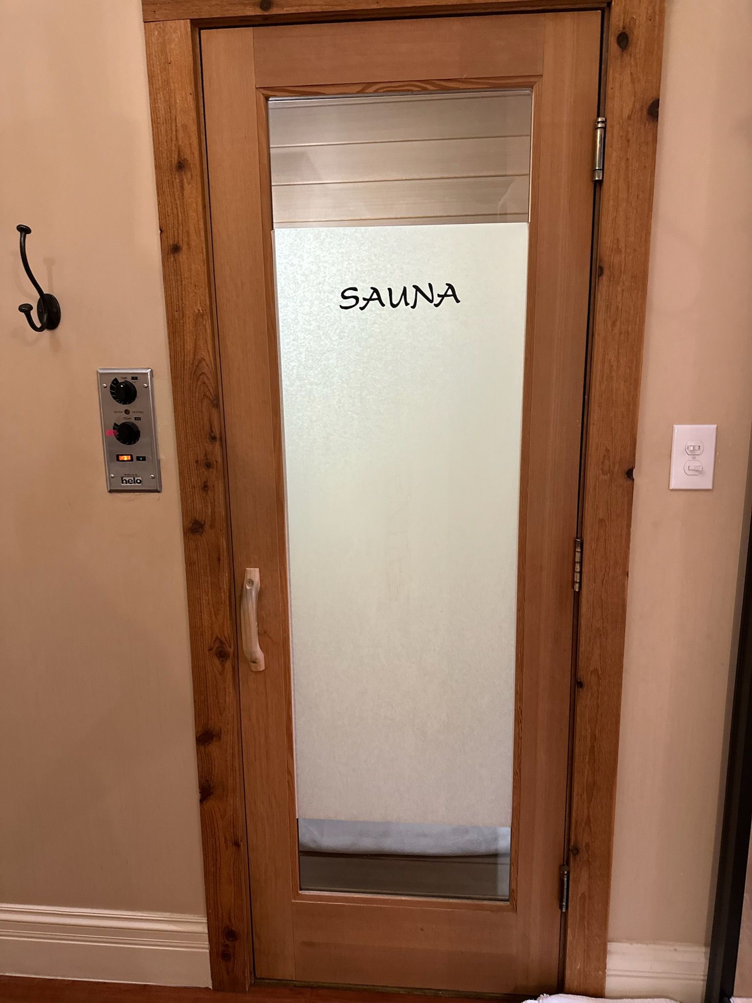 A wood-paneled sauna interior lit by numerous small candles, with a wooden bucket and ladle on a slatted bench.